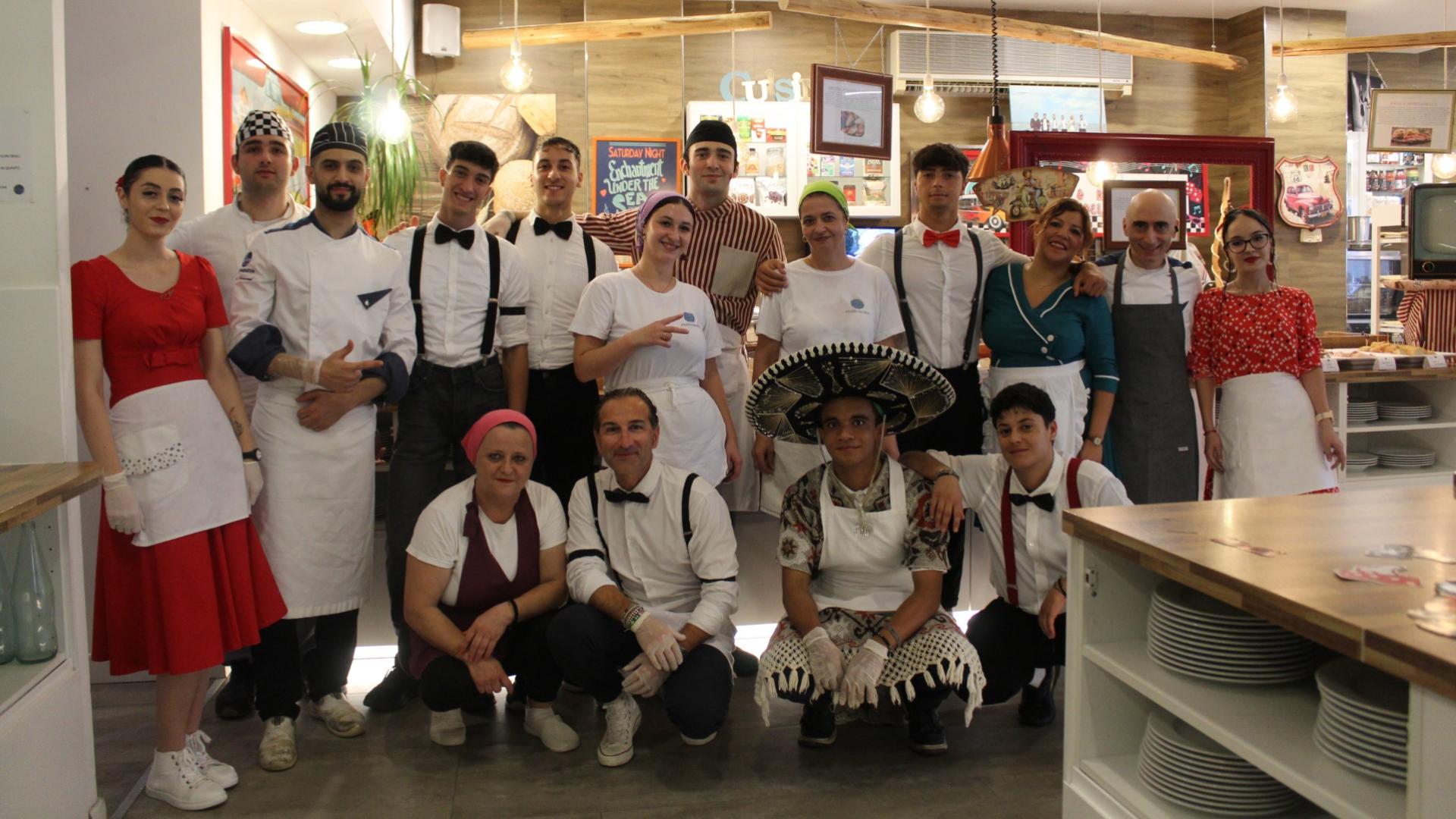Gruppo di persone in abiti da lavoro in un ristorante, sorridenti e posizionati per una foto.