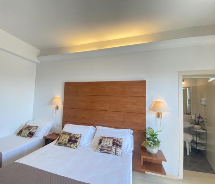 Camera da letto con letto matrimoniale, testiera in legno e bagno annesso.